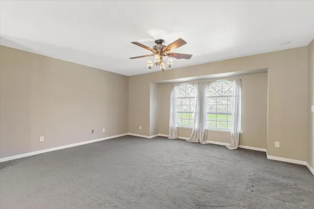 an empty room with wooden floor fireplace cabinet and windows
