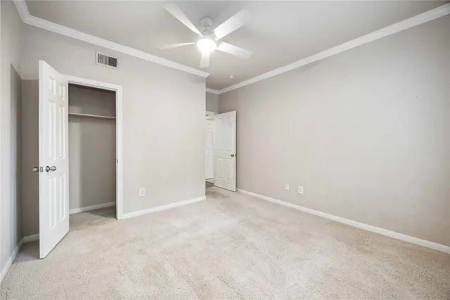 an empty room with closet and a ceiling fan