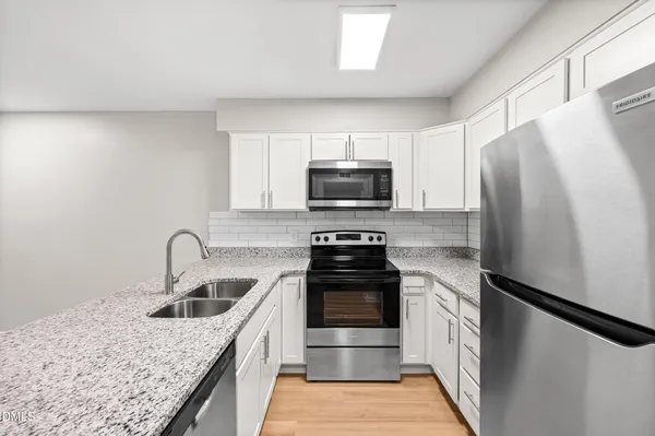 a kitchen with a sink a refrigerator and a stove top oven
