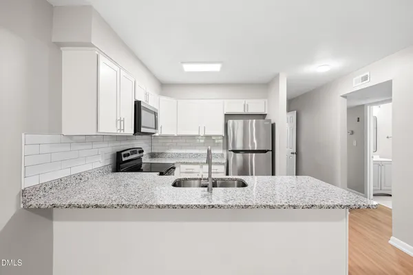 a kitchen with granite countertop a sink stainless steel appliances and white cabinets