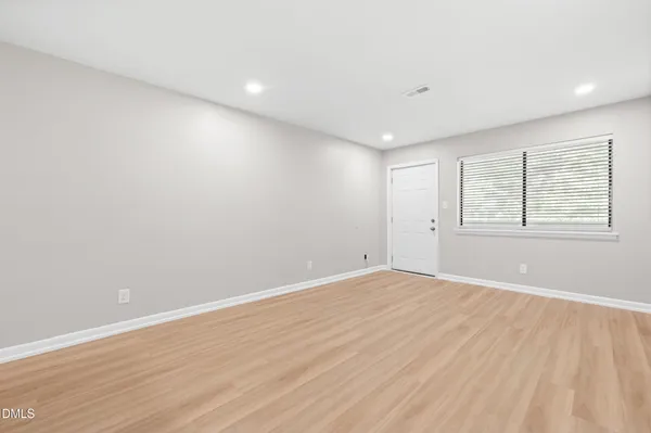 a view of an empty room with wooden floor and a window