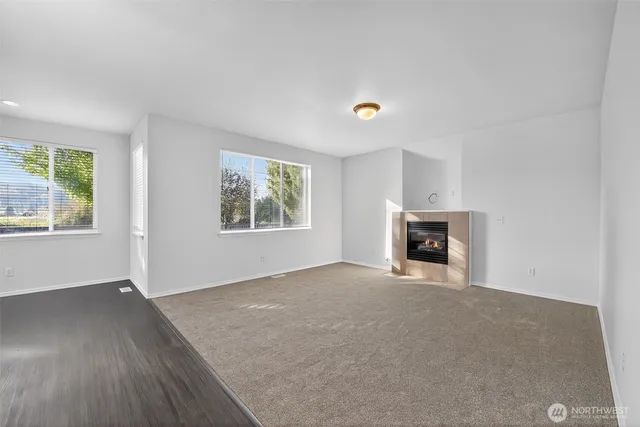 an empty room with windows and fireplace