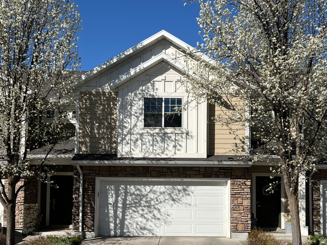 View of front of home with stone siding, an attached garage, and concrete driveway