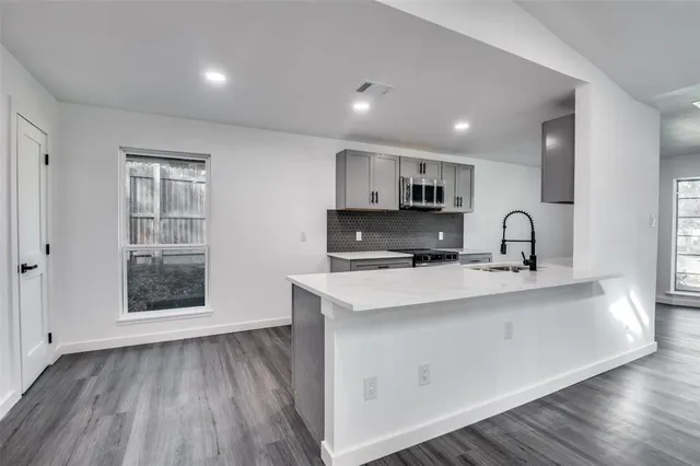 a view of kitchen with stainless steel appliances granite countertop a stove a sink and a microwave