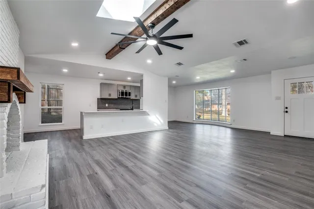 a view of an empty room with wooden floor and a ceiling fan