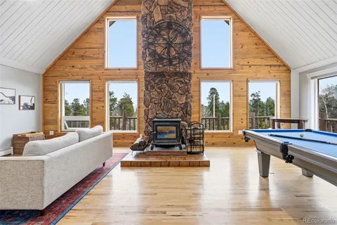 a living room with fireplace furniture and floor to ceiling windows