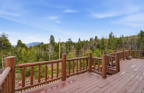 a view of a roof deck with wooden floor and fence with a floor to ceiling window