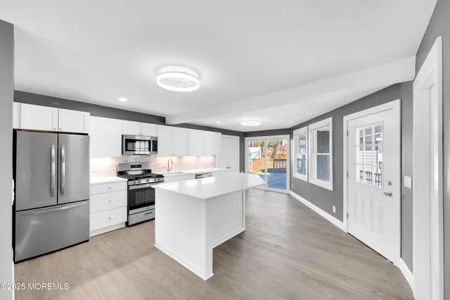 a kitchen with kitchen island a sink appliances and cabinets