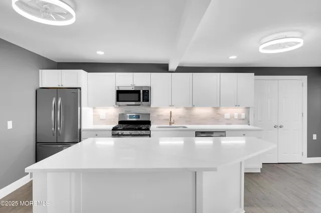 a kitchen with kitchen island a white cabinets and black appliances