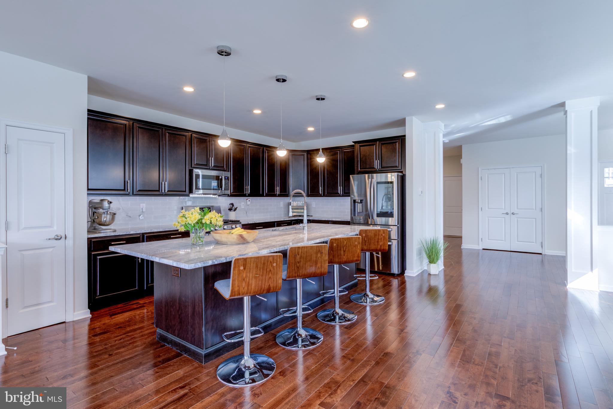 3044 Marias Way Garnet Valley, PA 19060 - Photo 11 of 63 a kitchen with stainless steel appliances granite countertop a table chairs a refrigerator and microwave