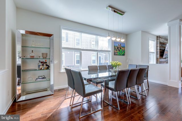 a kitchen with stainless steel appliances granite countertop a stove a refrigerator a sink a dining table and chairs with wooden floor