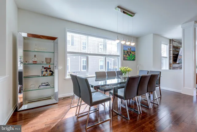 a kitchen with stainless steel appliances granite countertop a stove a refrigerator a sink a dining table and chairs with wooden floor