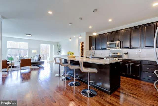 a kitchen with stainless steel appliances granite countertop a stove a refrigerator a sink a stove a dining table and chairs with wooden floor