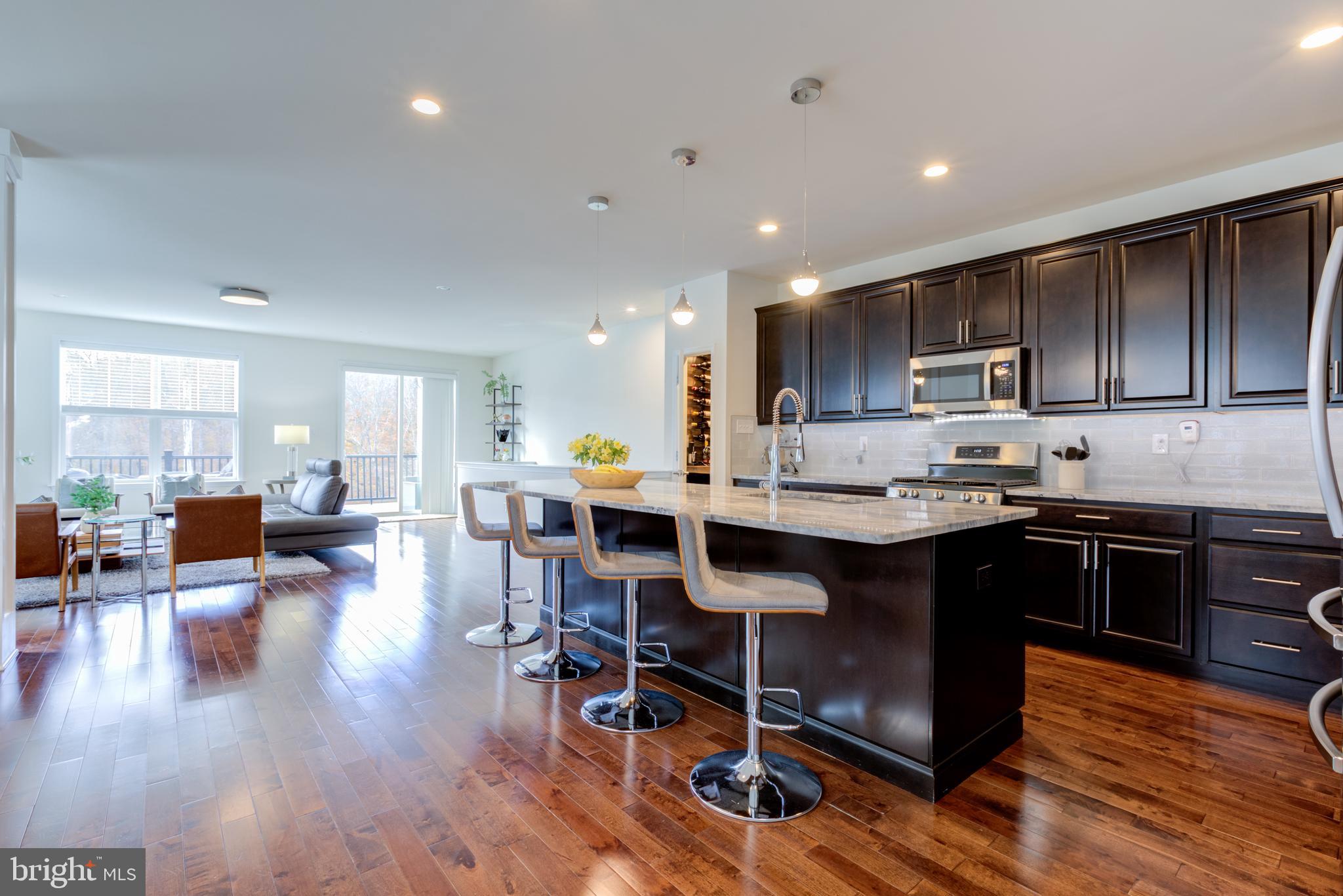 3044 Marias Way Garnet Valley, PA 19060 - Photo 8 of 63 a kitchen with stainless steel appliances granite countertop a stove a refrigerator a sink a dining table and chairs with wooden floor