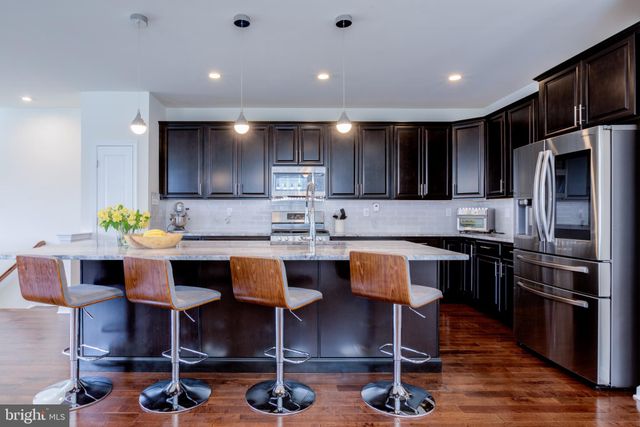 a dining room with stainless steel appliances kitchen island granite countertop a dining table chairs and granite counter tops