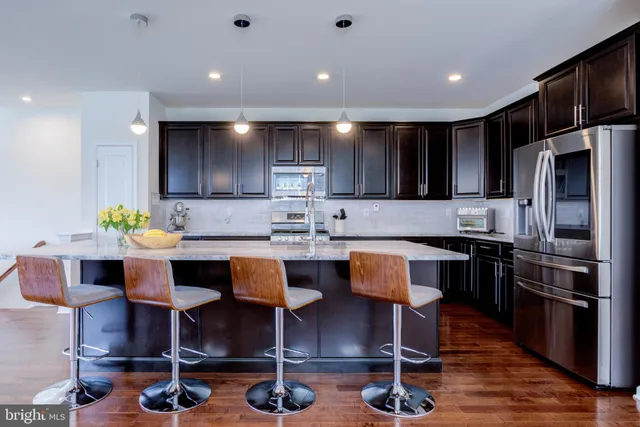 a dining room with stainless steel appliances kitchen island granite countertop a dining table chairs and granite counter tops