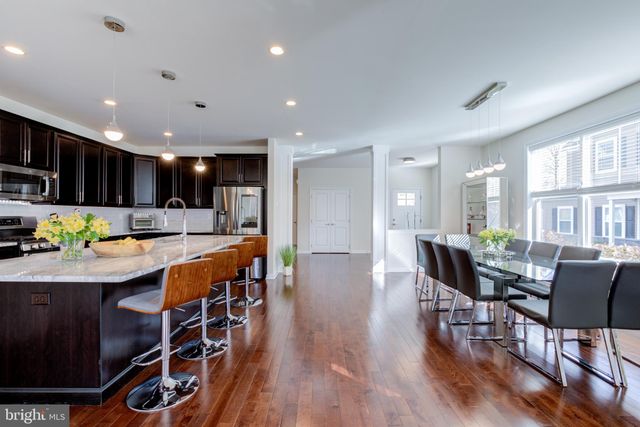 a kitchen with stainless steel appliances granite countertop a table chairs a refrigerator and microwave