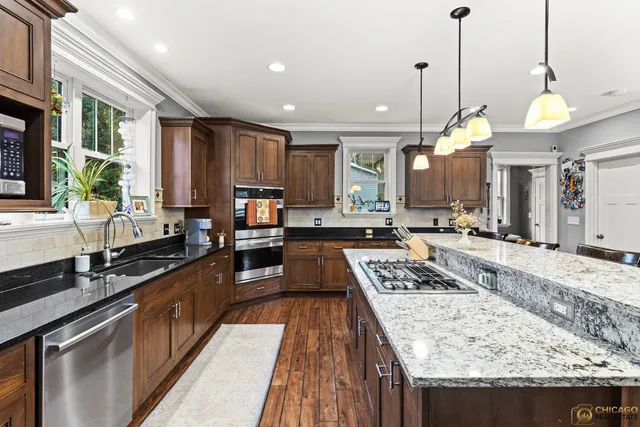 a large kitchen with kitchen island a large counter top space a sink stainless steel appliances and cabinets