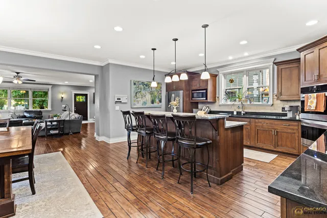 a view of a dining room and livingroom with furniture wooden floor a rug a fireplace and a chandelier
