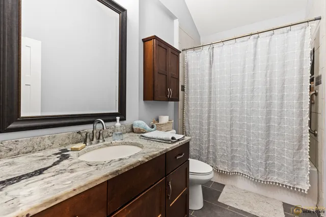 a bathroom with a granite countertop sink toilet and shower