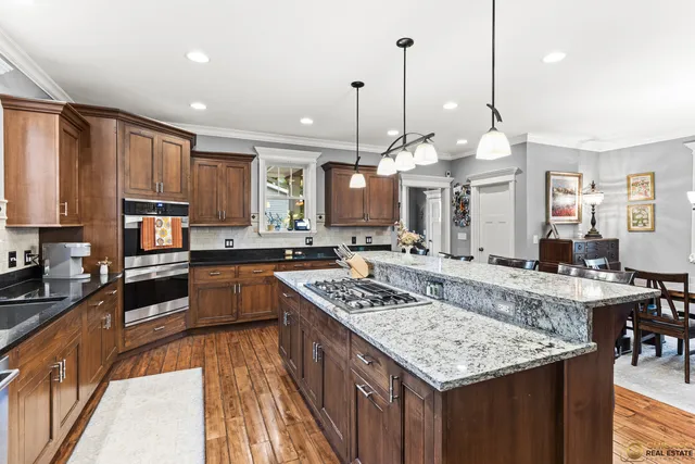 a kitchen with stainless steel appliances granite countertop a stove top oven a refrigerator a sink and dishwasher with wooden floor