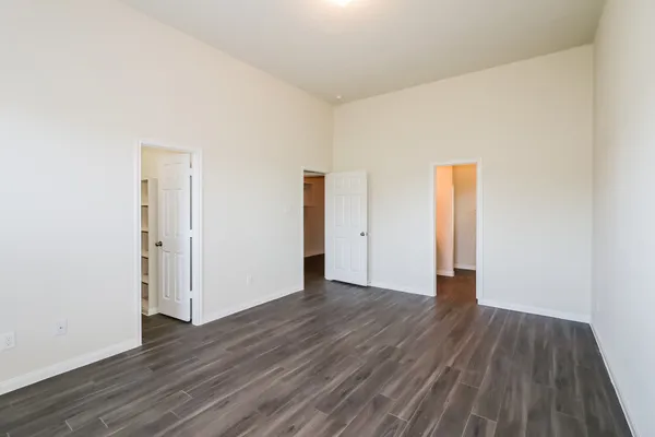 a view of an empty room with wooden floor and closet