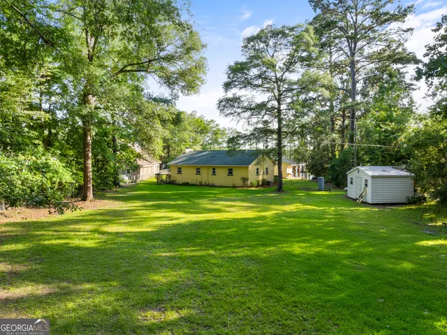 a view of a big house with a big yard and large trees