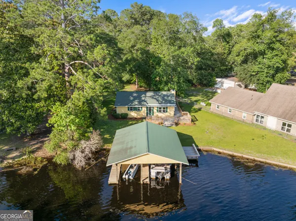 an aerial view of a house with garden space and trees all around