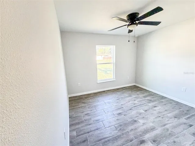 an empty room with a window and a fan