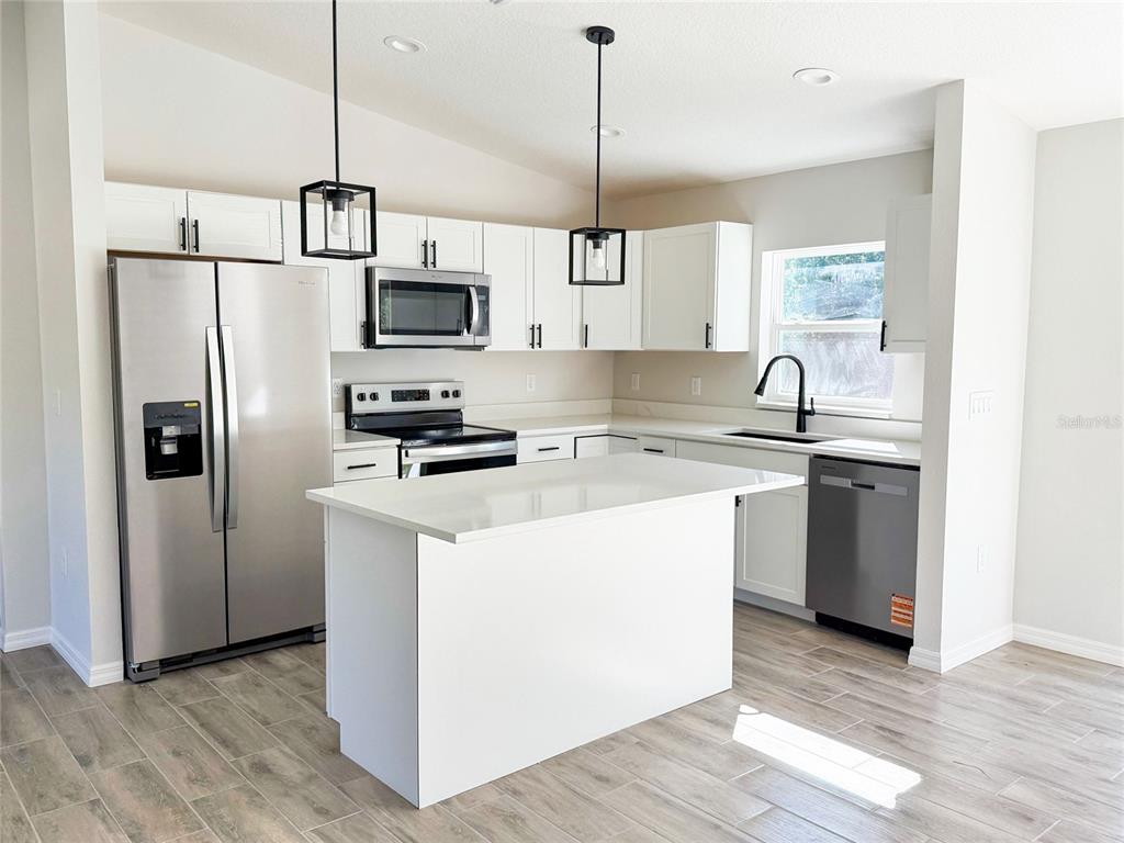 14390 Southwest 30th Place Ocala, FL 34481 - Photo 10 of 16 a kitchen with stainless steel appliances granite countertop a refrigerator a sink a stove a microwave and a wooden floor