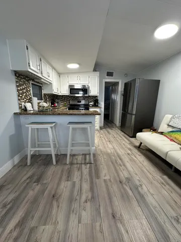 a kitchen with stainless steel appliances a sink a stove a refrigerator cabinets and wooden floor