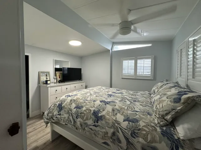 a bed sitting in a spacious bedroom next to a window and a flat screen tv