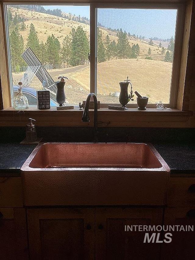1000 Pardee Road Kamiah, ID 83536 - Photo 21 of 50 Hammered copper apron-front sink with a dark-finish countertop and wood cabinetry below