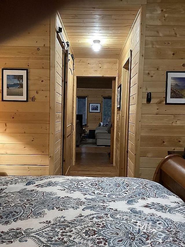 1000 Pardee Road Kamiah, ID 83536 - Photo 25 of 50 Wood-paneled hallway featuring a ceiling-mounted light fixture, sliding barn doors, and wood-finish flooring visible in the distance