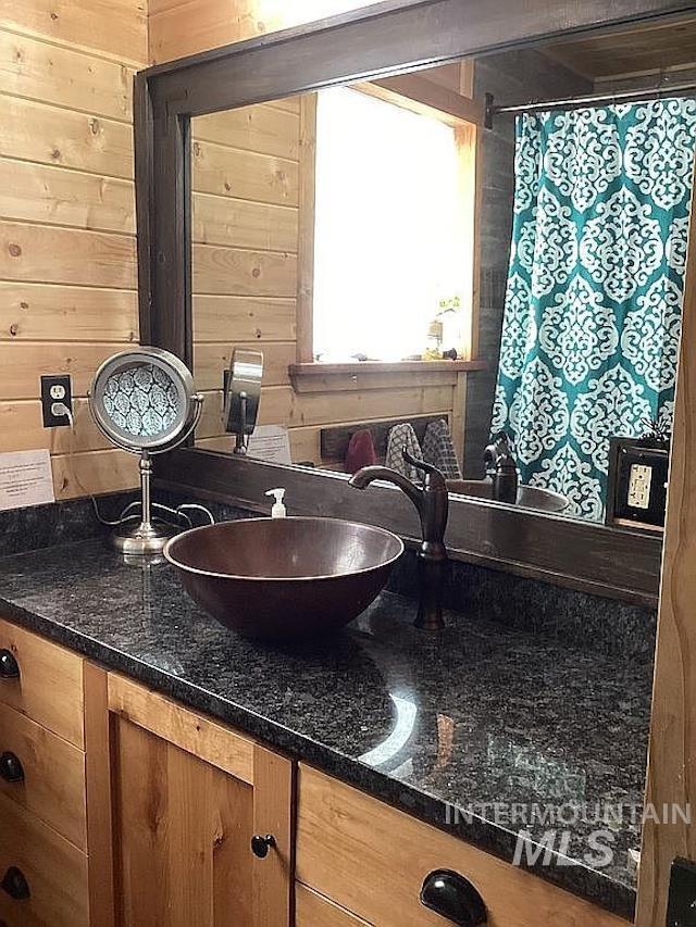 1000 Pardee Road Kamiah, ID 83536 - Photo 26 of 50 Vanity featuring a vessel sink with bronze-finish faucet, dark granite-patterned countertop, and wood cabinetry