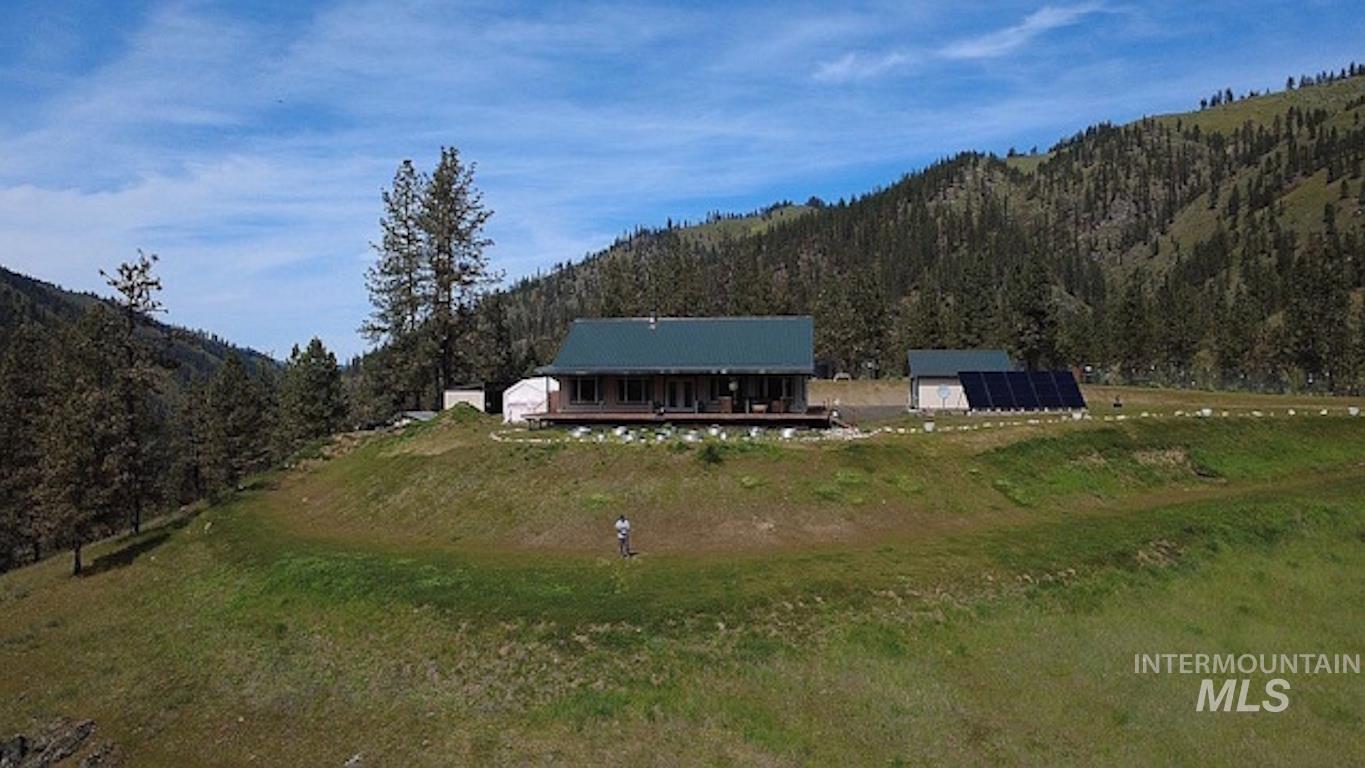 1000 Pardee Road Kamiah, ID 83536 - Photo 4 of 50 Cabin-style home featuring a covered porch, expansive green space, surrounding mountainous terrain, and an outbuilding with solar panels