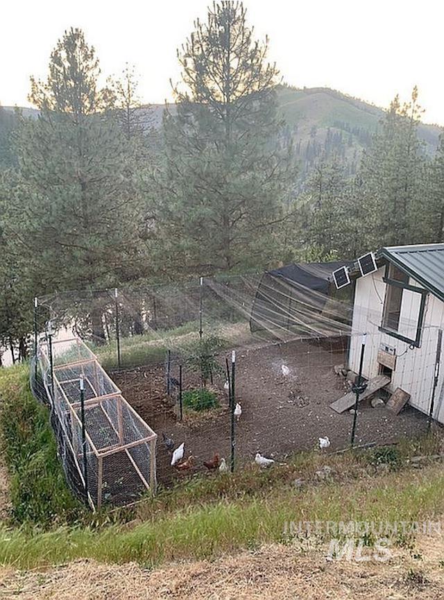 1000 Pardee Road Kamiah, ID 83536 - Photo 49 of 50 Outdoor enclosure featuring a small white structure with a green metal roof, a fenced perimeter, and multiple small solar panels