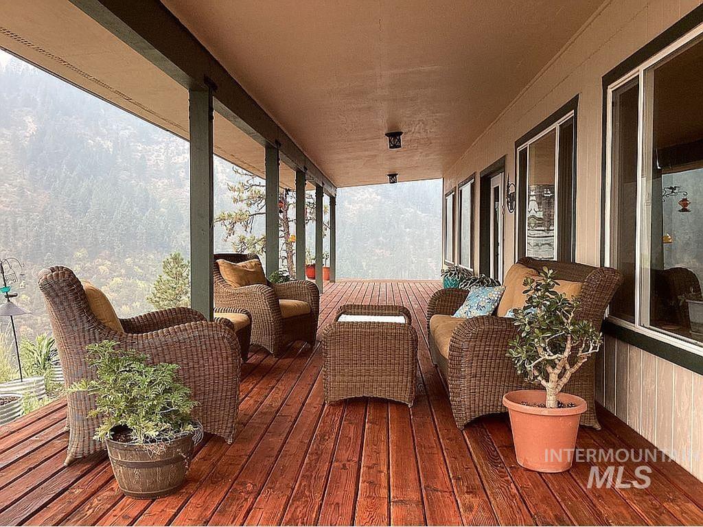 1000 Pardee Road Kamiah, ID 83536 - Photo 6 of 50 Expansive covered patio featuring wood-finish decking, multiple large windows, and a scenic tree-covered landscape backdrop