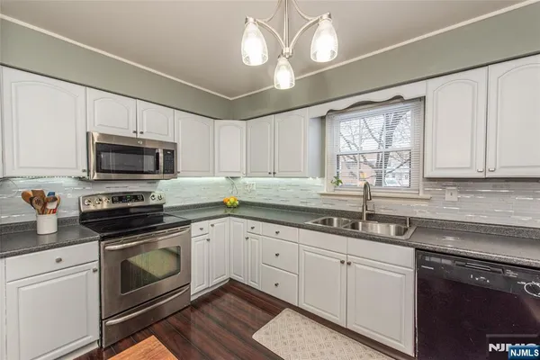 a kitchen with a refrigerator a sink dishwasher a stove and white cabinets with wooden floor