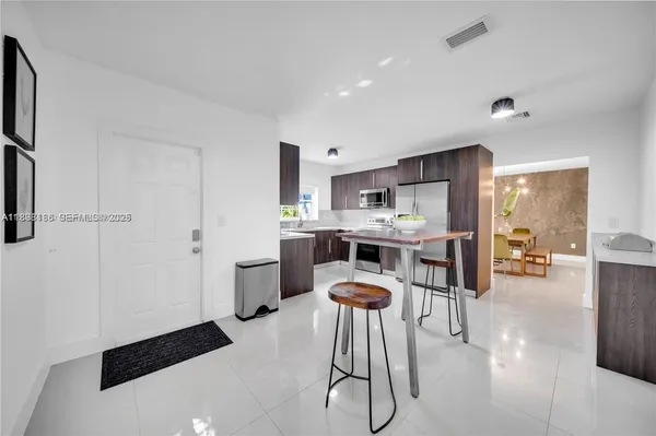 a kitchen with stainless steel appliances a refrigerator a stove a sink dishwasher and white cabinets with wooden floor