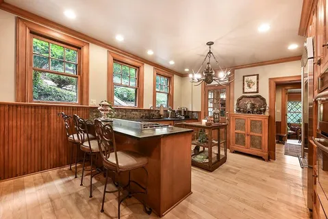 a view of a dining room with furniture a chandelier and large windows