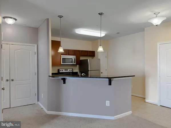a view of a kitchen with stainless steel appliances wooden floor and living room view