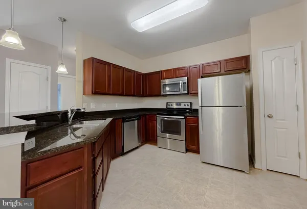 a kitchen with stainless steel appliances granite countertop a refrigerator stove and sink