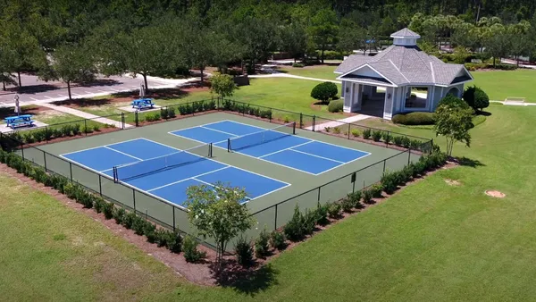 a view of a tennis ground with large trees