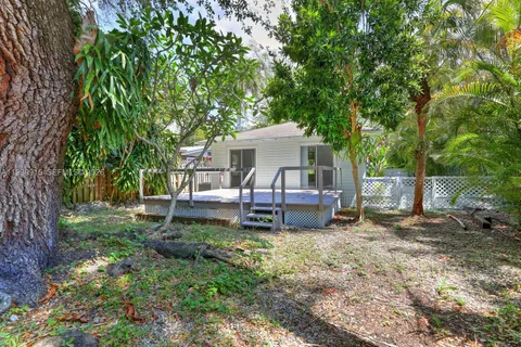 a view of a house with a yard deck and a large tree