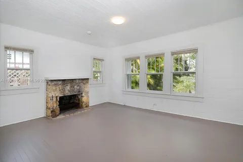 an empty room with windows and fireplace
