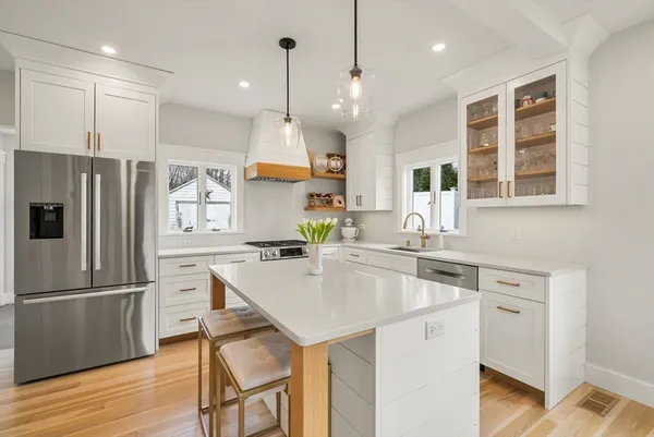 a kitchen with a refrigerator a sink and wooden floor