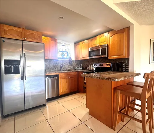 a kitchen with stainless steel appliances granite countertop a refrigerator a stove a sink a dining table and chairs