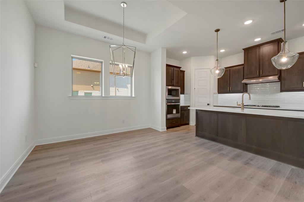 1908 Cola Drive Van Alstyne, TX 75495 - Photo 19 of 29 Open-concept kitchen and dining area featuring wood-finish flooring, recessed lighting, and a tray ceiling