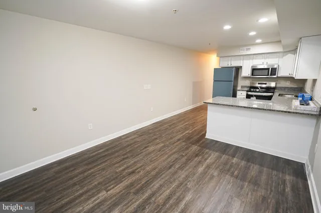 a kitchen with stainless steel appliances a microwave a stove a sink and white cabinets with wooden floor